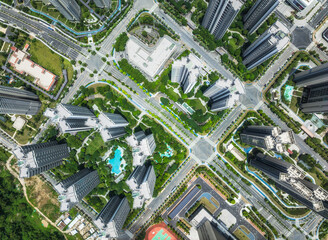 Aerial view of a modern city intersection with residential buildings, green parks, and a symmetric...