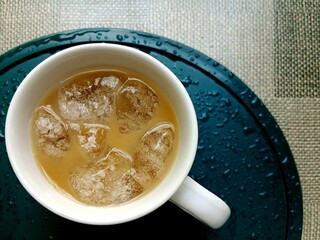 Top view of a mug of iced coffee on a round tray. A refreshing coffee drink.