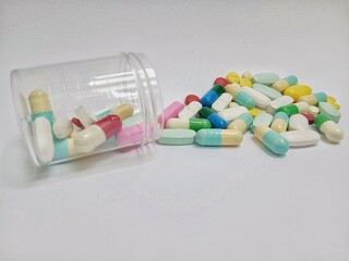 Pills, capsules and tablets spilling out of their packaging on a white background. Illustration of...
