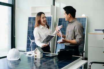 Two Asian engineers collaborate on a solar and wind energy project, discussing innovation and...