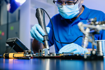 Technician in gloves performs precise soldering on circuit board using hot air gun. Concept of...
