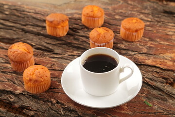 Morning foods-  fresh cup of coffee and baked muffins served in a cafe background.