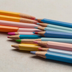 Fototapeta premium Pastel colored pencils arranged in a row on a neutral surface