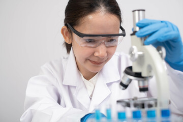 A focused scientist in a lab coat examines samples through a microscope, embodying dedication to...