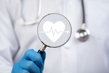 A healthcare professional examines a magnifying glass with a heart symbol and heartbeat line,...