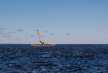 Floating crane on a platform at sea on a summer day.