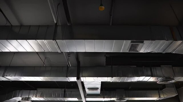 Metal ductwork runs along a dark ceiling with sparse lighting