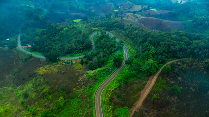 Aerial view of a road surrounded by forest on a foggy morning in the rainy season. Aerial view of...
