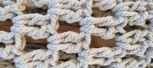 Detailed close-up of macrame knots made from natural cotton rope, showcasing texture and craftsmanship in a neutral color palette. Ideal for craft, DIY, and textile themes