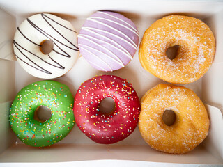 Donuts with different colorful icing designs arranged in a box.