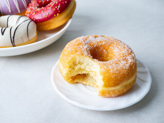 Donuts with sugar sprinkles with bite mark on a white background.