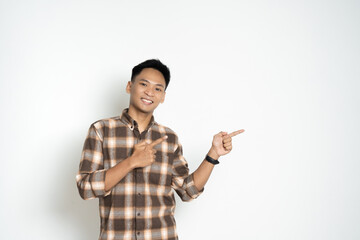A cheerful man in a plaid shirt standing against a white background, pointing toward a direction. Ideal for concepts portraying direction, guidance, and cheerful expressions.