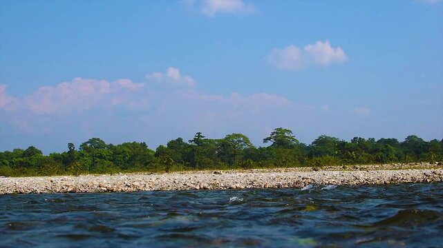 Wild Mountain River Flows Through Stone Boulders and Rocks. Murti Riverbed in foreground with flowing water and stones. Dooars, India. Small cascade from rocks in national park.