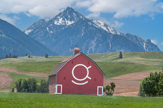 Iconic wooden red barn in Eastern Oregon with the Cascade Mountains in the background