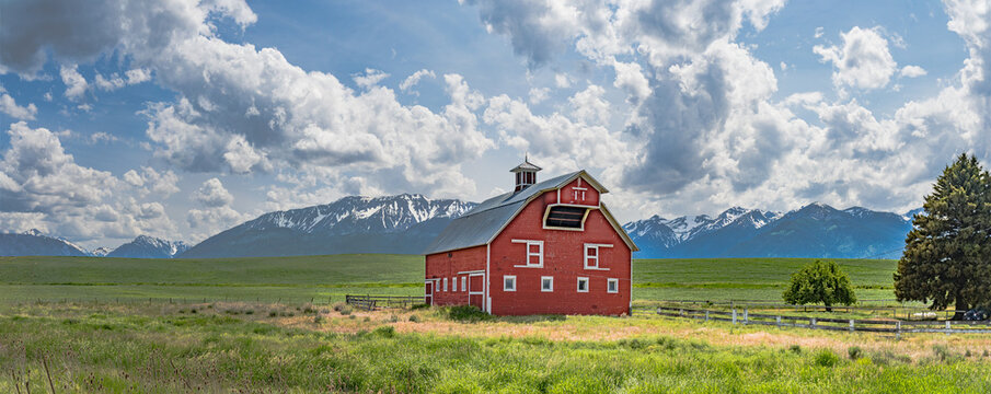 Iconic wooden red barn in Eastern Oregon with the Cascade Mountains in the background