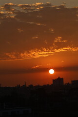 Sunset over a calm sky with orange hues and clouds.