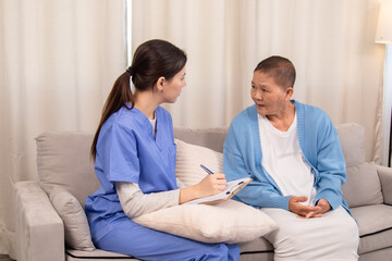 Young nurse in uniform listening attentively to an senior woman on a couch, expressing support and...