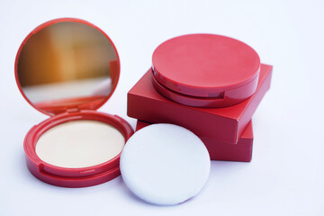 Red compact foundation face powder with matching red packaging box, featuring a built-in mirror and...
