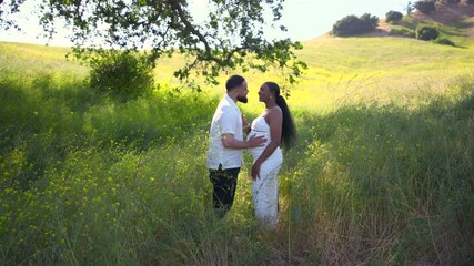 A lovely couple shares a romantic moment in a beautiful and vibrant outdoor setting, celebrating their love for one another and the exciting journey that comes with impending parenthood together