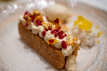 A tart with cream on top, with vanilla ice cream and crumble served on plate.
