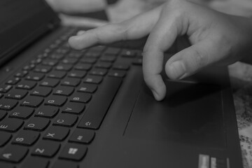 Monochrome photographic image of hand on laptop touchpad modern tech aesthetic digital work concept...