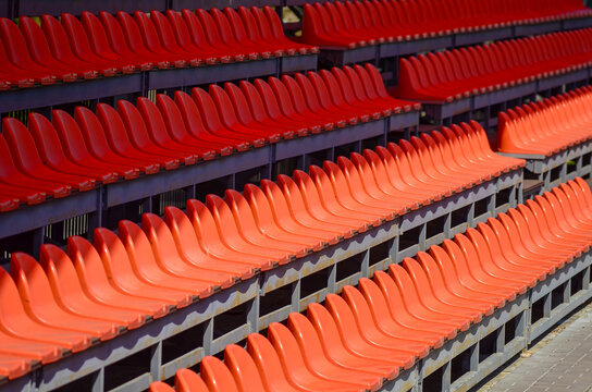 A row of red seats are empty. The seats are arranged in a row, w