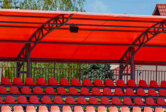 A red canopy with a row of red chairs underneath it. The chairs