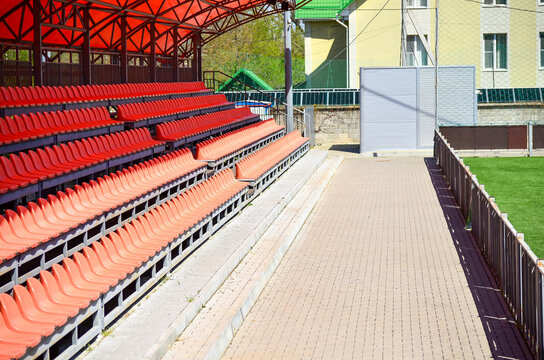 A stadium with red seats and a brick walkway. The stadium is emp