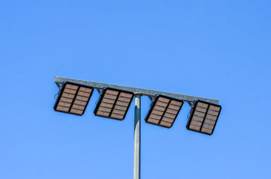 A tall pole with four lights on it. The lights are black and the