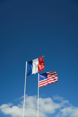 Obraz na płótnie Canvas american and french flags in normandy france agains a blue sky