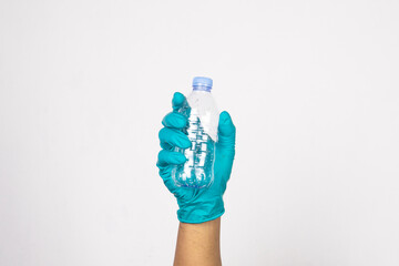 Hand wearing work gloves is holding an empty plastic bottle isolated on white background