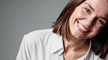 Smiling woman with medium-length hair wearing a white shirt in a studio setting