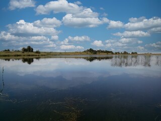 Reflections of the blue sky and white clouds in the clear lake water