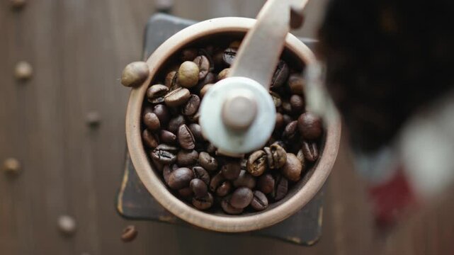 Grinding of aromatic coffee beans with a manual coffee grinder. Smooth rotation of the camera. Top view
