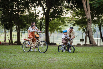 A man and two children ride bikes in a park. One of the children is wearing a helmet