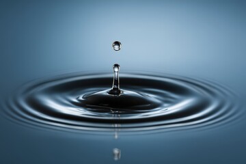 Captivating moment of a water droplet piercing the surface creating dynamic ripples and light reflections in serene blue backdrop emphasizing fluid dynamics and tranquility