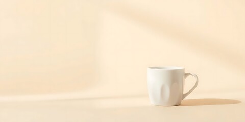 Fototapeta premium Solitary white cup casting shadow against creamy beige backdrop, stillness