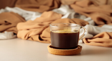 Black coffee in glass cup on a beige background.