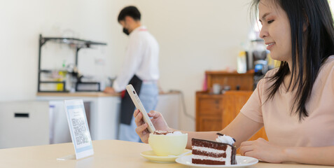 Woman use smartphone to scan QR code to pay in cafe restaurant with a digital payment without cash....