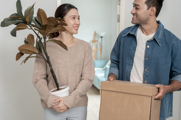 Moving house, relocation. Couples hold carton box contain equipment for new condominium, inside the...