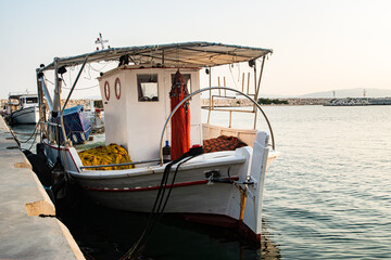 Vintage Mediterranean fishing boat docked at a peaceful harbor during golden hour