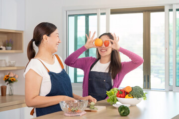 Healthy Lifestyle and Fun Cooking. Two women enjoying playful moments with fruits in a bright kitchen.