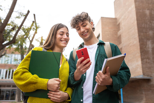 Smiling university students using smartphone on campus