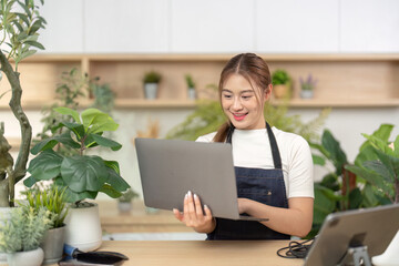 Remote Work and Engagement. Happy young woman holding laptop and smiling in a vibrant indoor garden setting.