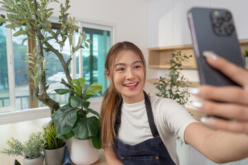 Selfie Moment in Indoor Garden. Young woman taking selfie with smartphone surrounded by plants.
