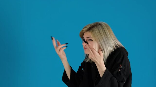 Young woman wildly flails arms during argument on blue background. Lady tries to emphasize point with frustration clearly boiling over