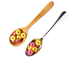corn rings and strawberry rings in a metal spoon isolated on white background, top view. corn flakes fruity loops colorful hoops.