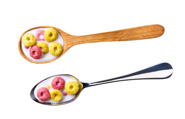 corn rings and strawberry rings with milk in a metal spoon isolated on white background, top view. corn flakes fruity loops colorful hoops.