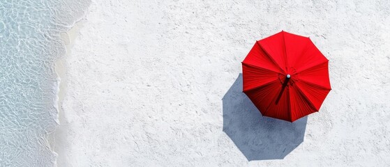 Red umbrella lying on a white sandy beach. the umbrella is open and appears to be empty, with no people or other objects in sight.