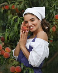 Beautiful happy young girl with peach garden in summer